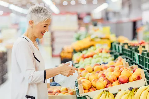 Frau kauft Obst ein, denn sie möchte ihre Vergesslichkeit mit einem gesunden Lebensstil behandeln
