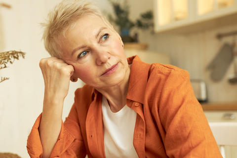 Frau stützt nachdenklich ihren Kopf auf die Hand