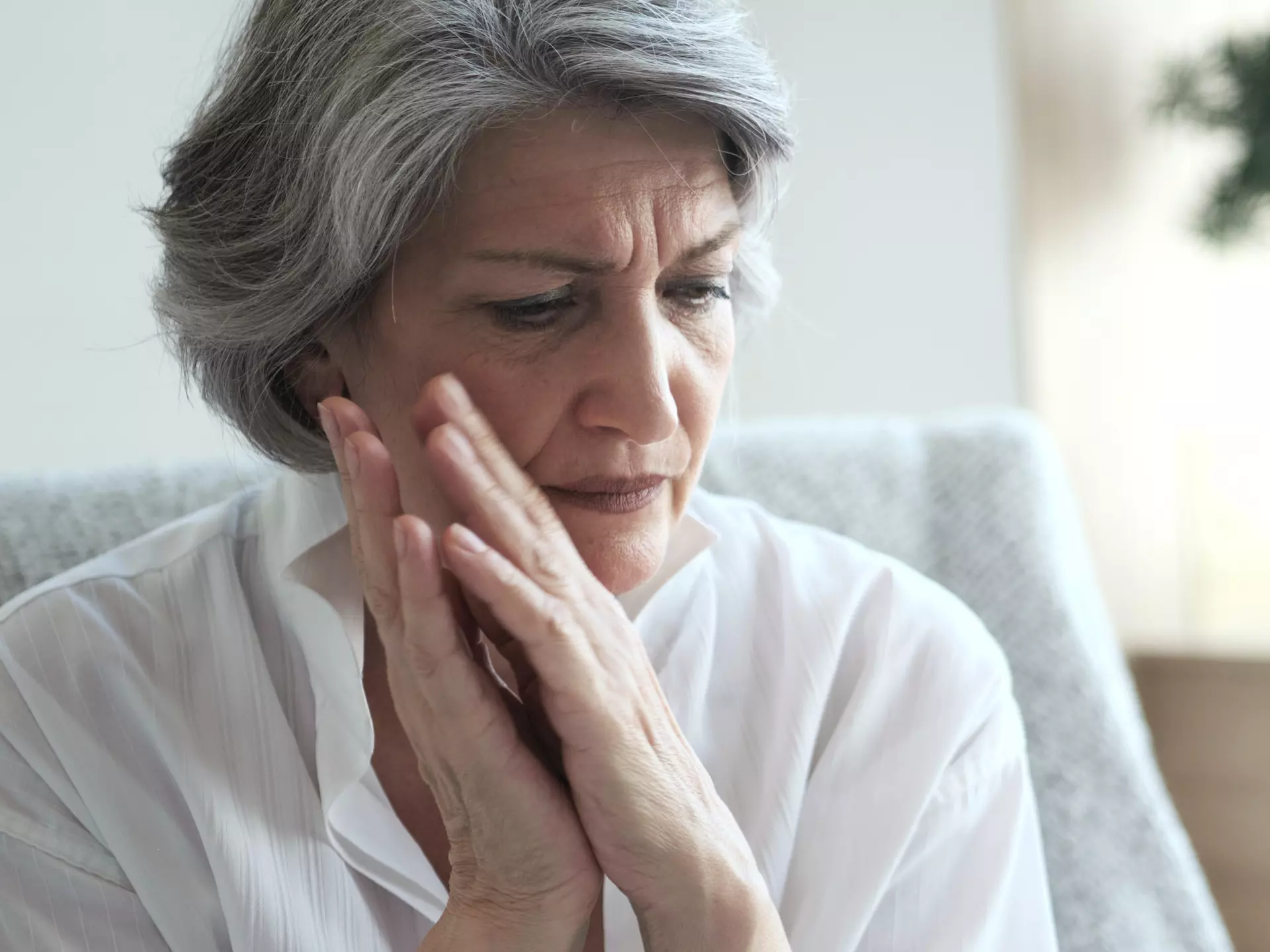 Ältere Frau die bedrückt ist, da sie unter Wortfindungsstörungen leidet
