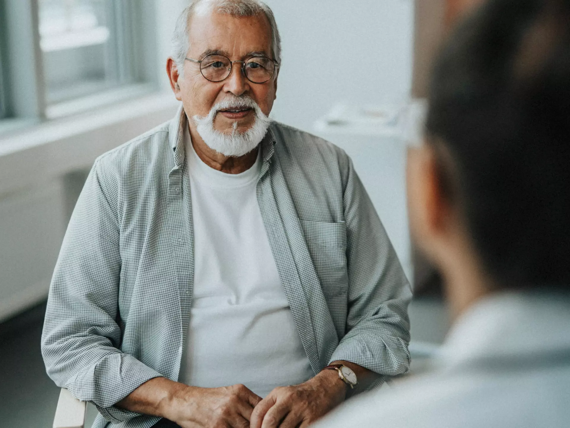 Ein älterer Herr mit Brille und Bart im Gespräch mit seinem Arzt