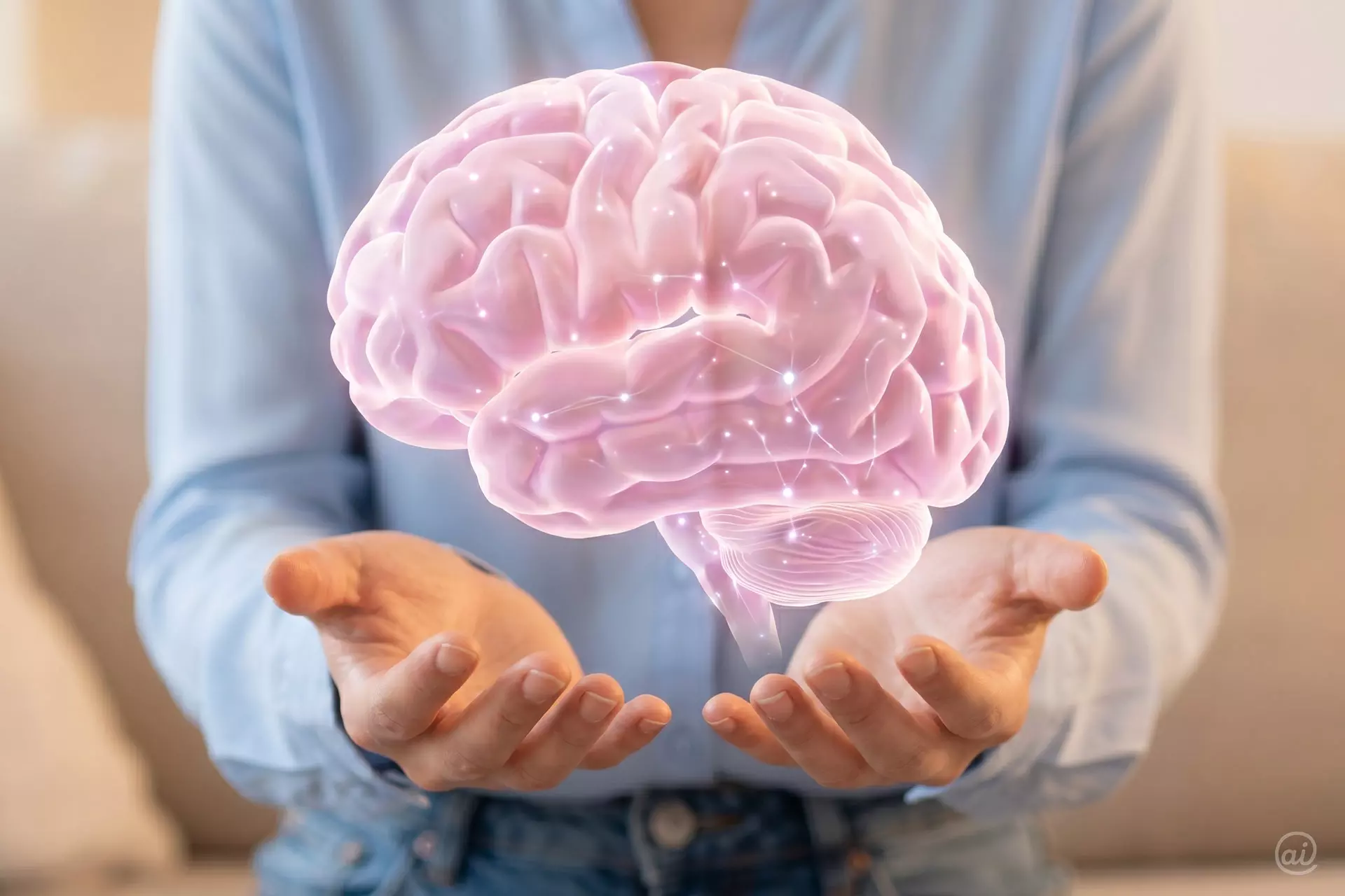 In den geöffneten Händen einer Frau schwebt ein rosafarbenes, transparentes Gehirnmodell, auf dem leuchtende Synapsen-Punkte aufblitzen.