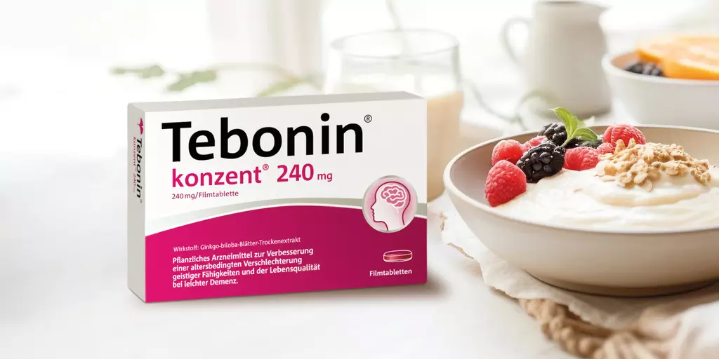 Eine Packung Tebonin® konzent® auf einem Tisch neben einem gesunden Frühstück mit Quark, Früchten und Fruchtsaft