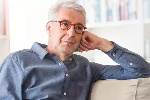 Mann sitzt auf dem Sofa und stützt sich auf