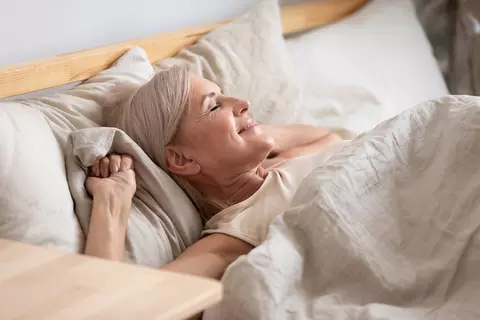 Frau liegt erholt im Bett