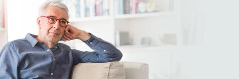 Mann sitzt auf dem Sofa und stützt sich auf