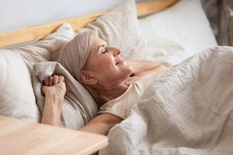 Frau liegt erholt im Bett